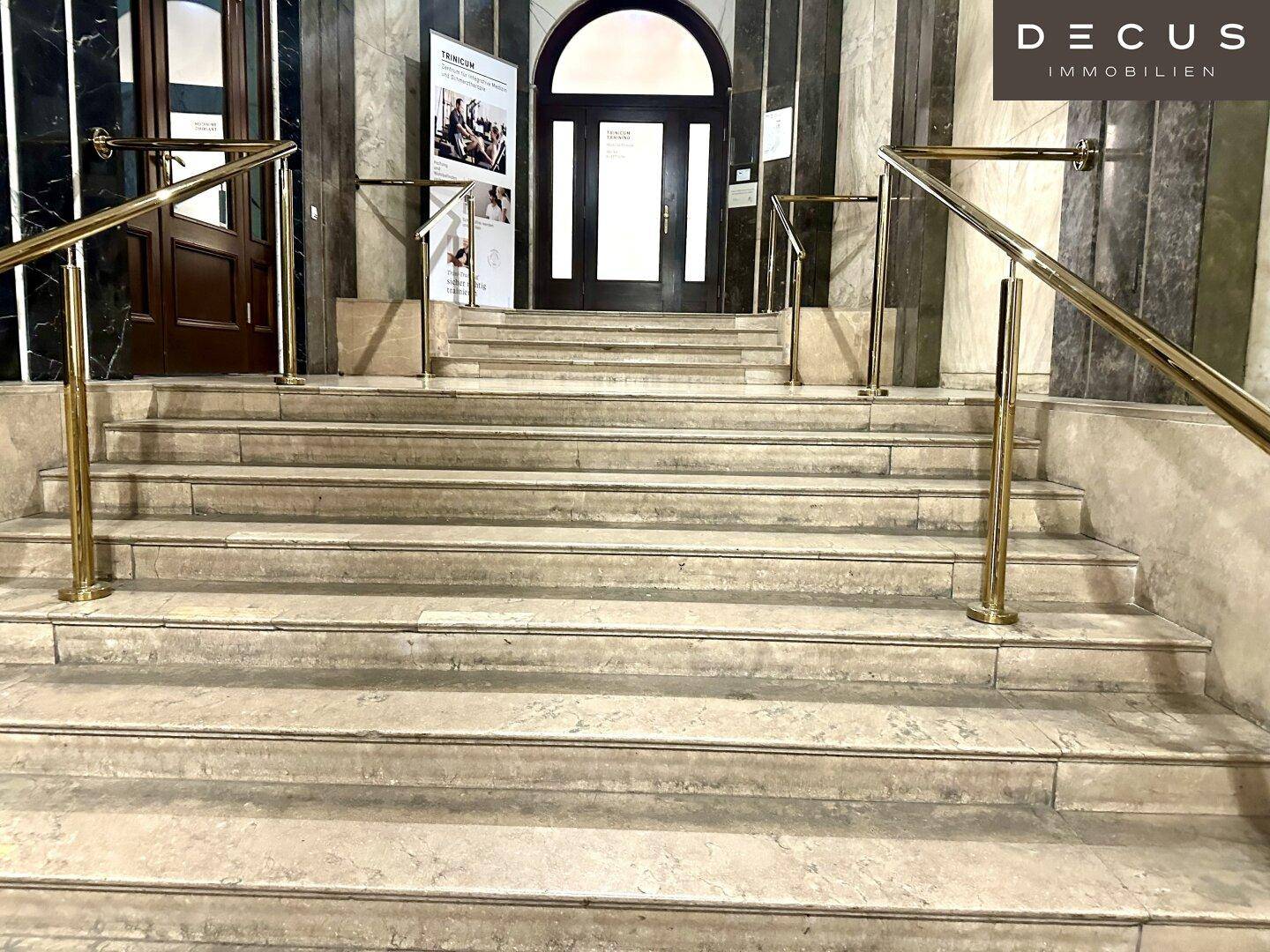 Elegante Steintreppe mit goldenen Handläufen und Marmorverkleidung im historischen Gebäude.
