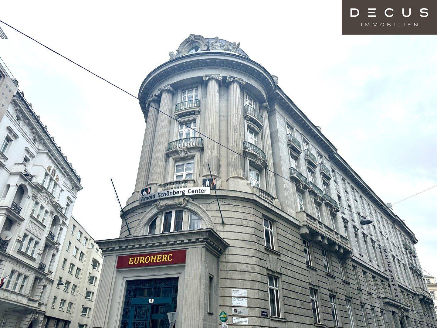 Historisches Eckgebäude mit klassischer Architektur und vielen Fenstern in städtischer Umgebung.
