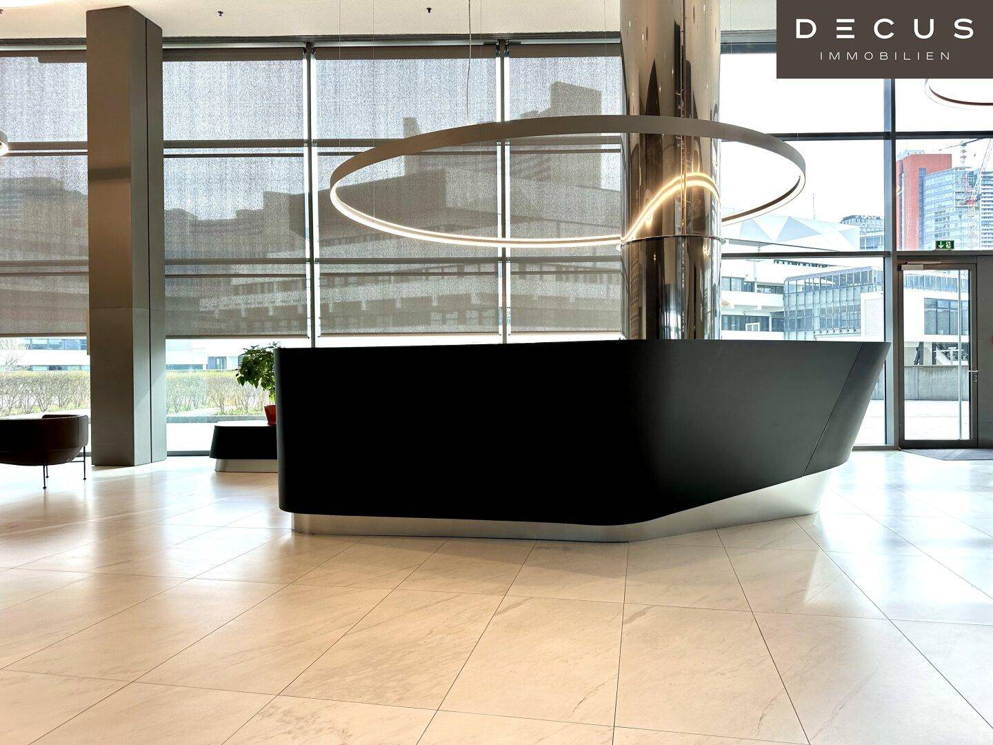Elegante, moderne Rezeptionstheke in einer hellen Lobby mit Marmorboden und großen Fensterfronten.