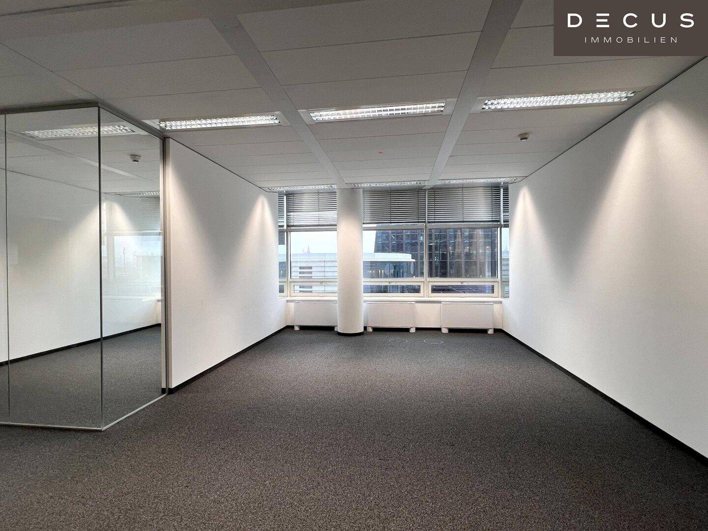 Modernes Büro mit Teppichboden und einer Glaswand, die den Raum optisch erweitert.