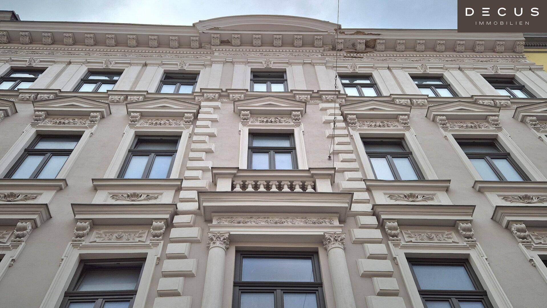 Historische Gebäudefassade mit reich verzierten Fenstern und Stuckelementen, klassische Architektur.