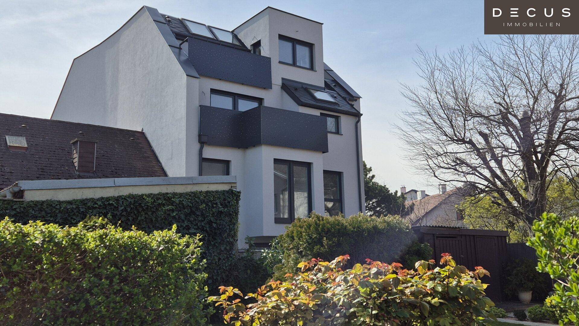 Moderne Gebäudefassade von der Gartenseite mit üppiger Bepflanzung und Bäumen.