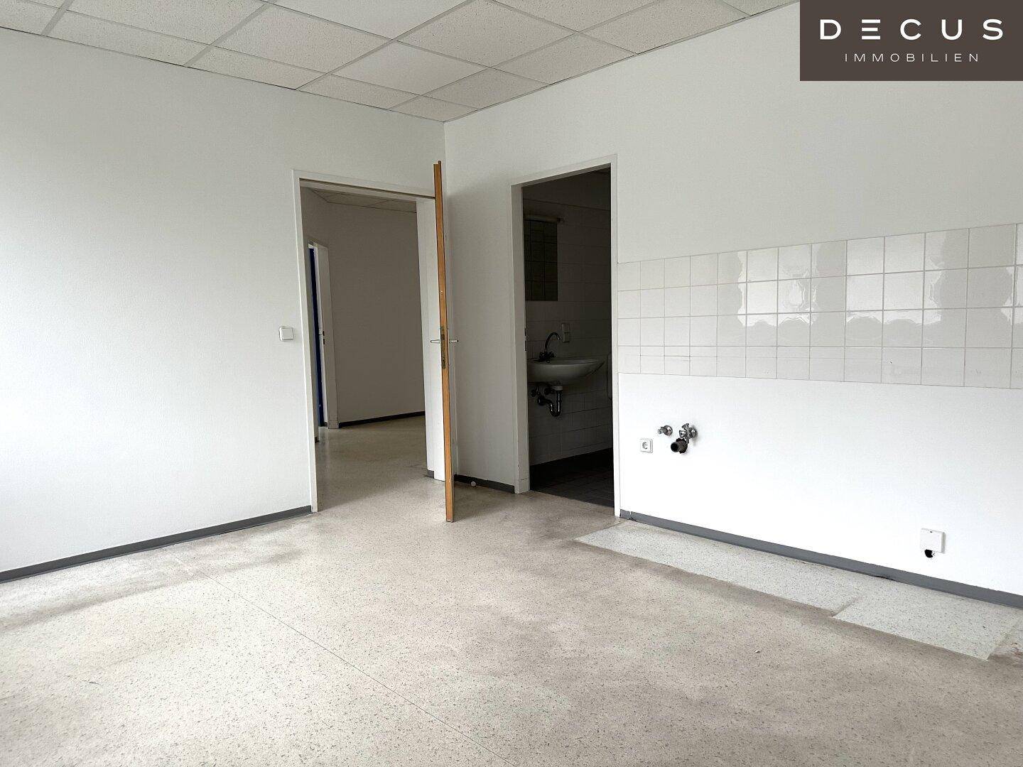 Vorbereiteter Bereich für eine Küchenzeile mit Fliesenwand und Waschbeckenanschluss.