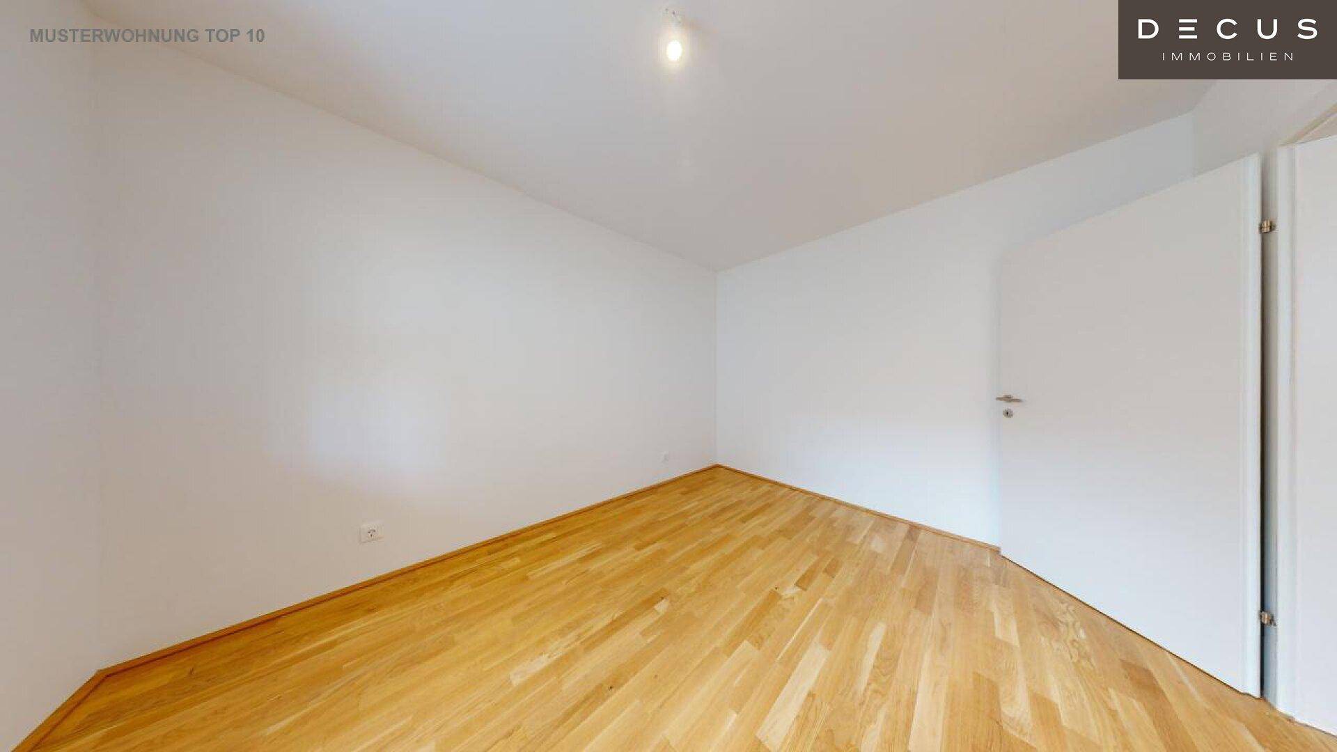 Leeres Schlafzimmer mit Parkettboden und weiß gestrichenen Wänden.