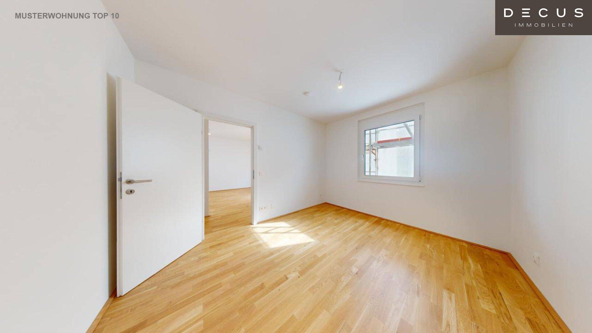 Helles Zimmer mit Parkettboden und Blick auf die Baustelle durch das Fenster.