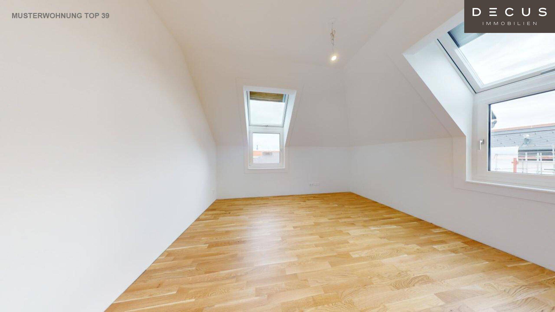 Schlafzimmer im Dachgeschoss mit schrägen Wänden und zwei Dachfenstern.