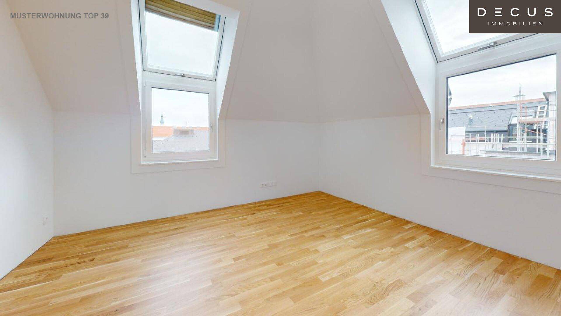 Helles Schlafzimmer im Dachgeschoss mit Parkettboden und Dachfenstern.