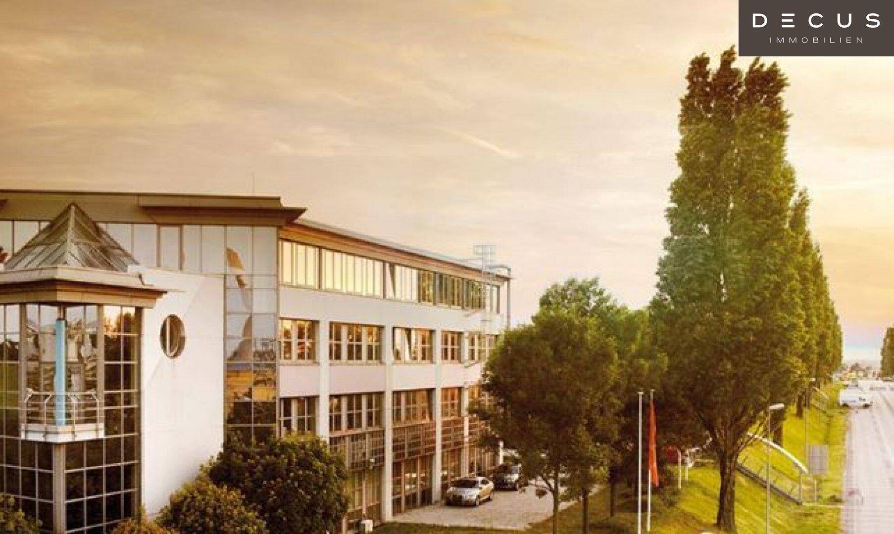 Ansicht der modernen Fassade eines Bürogebäudes mit großen Glasflächen und einem Eingangsbereich bei Sonnenuntergang.