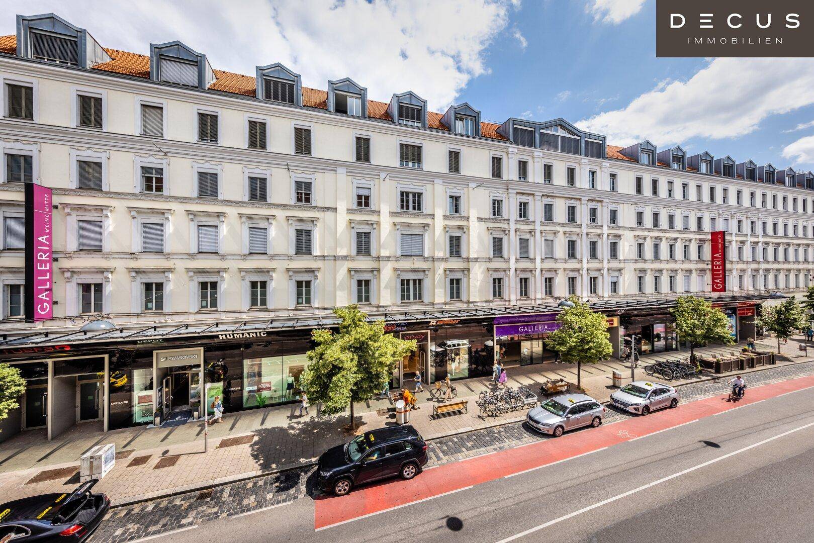 Historisches Gebäude mit Geschäften im Erdgeschoss und Wohnungen darüber, an einer belebten Straße gelegen.
