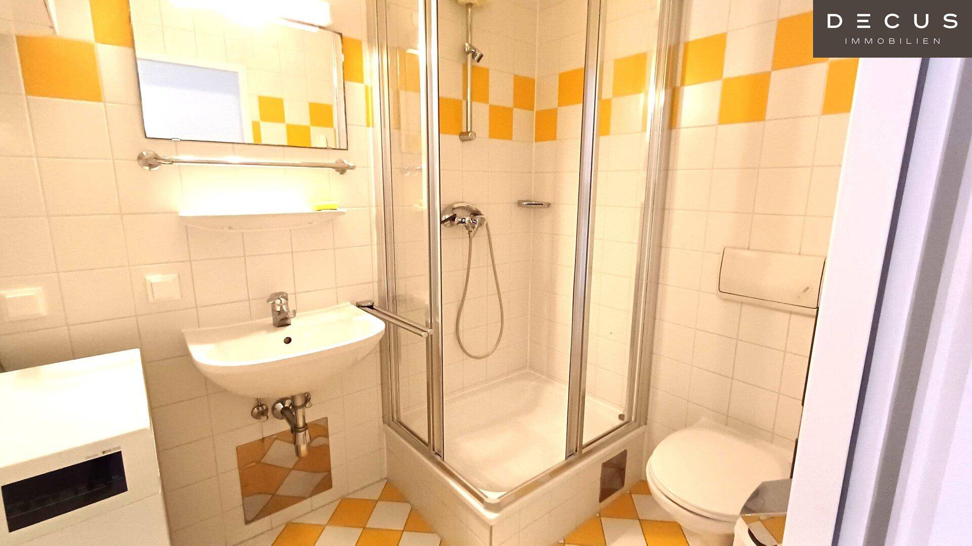 Kleines Badezimmer mit Duschkabine, Waschbecken und WC, dekoriert mit gelben Fliesen und Spiegelschrank.