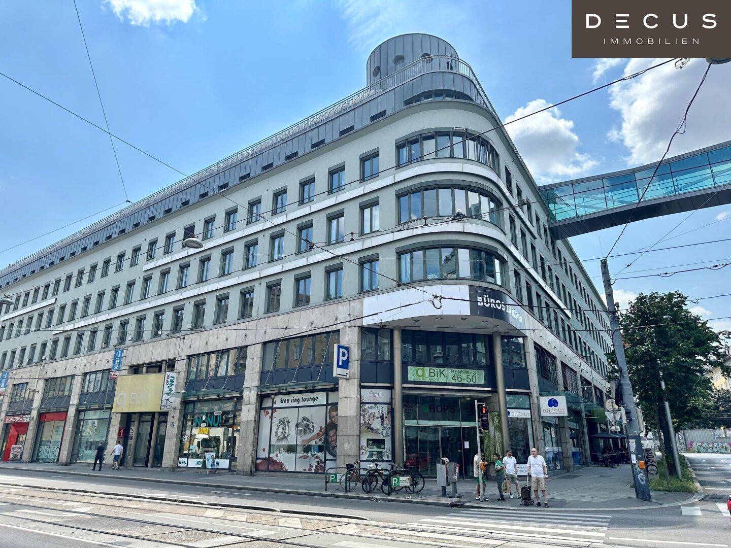 Weitläufige Ansicht eines modernen Geschäftsgebäudes mit geschwungener Fassade und Ladenflächen im Erdgeschoss.