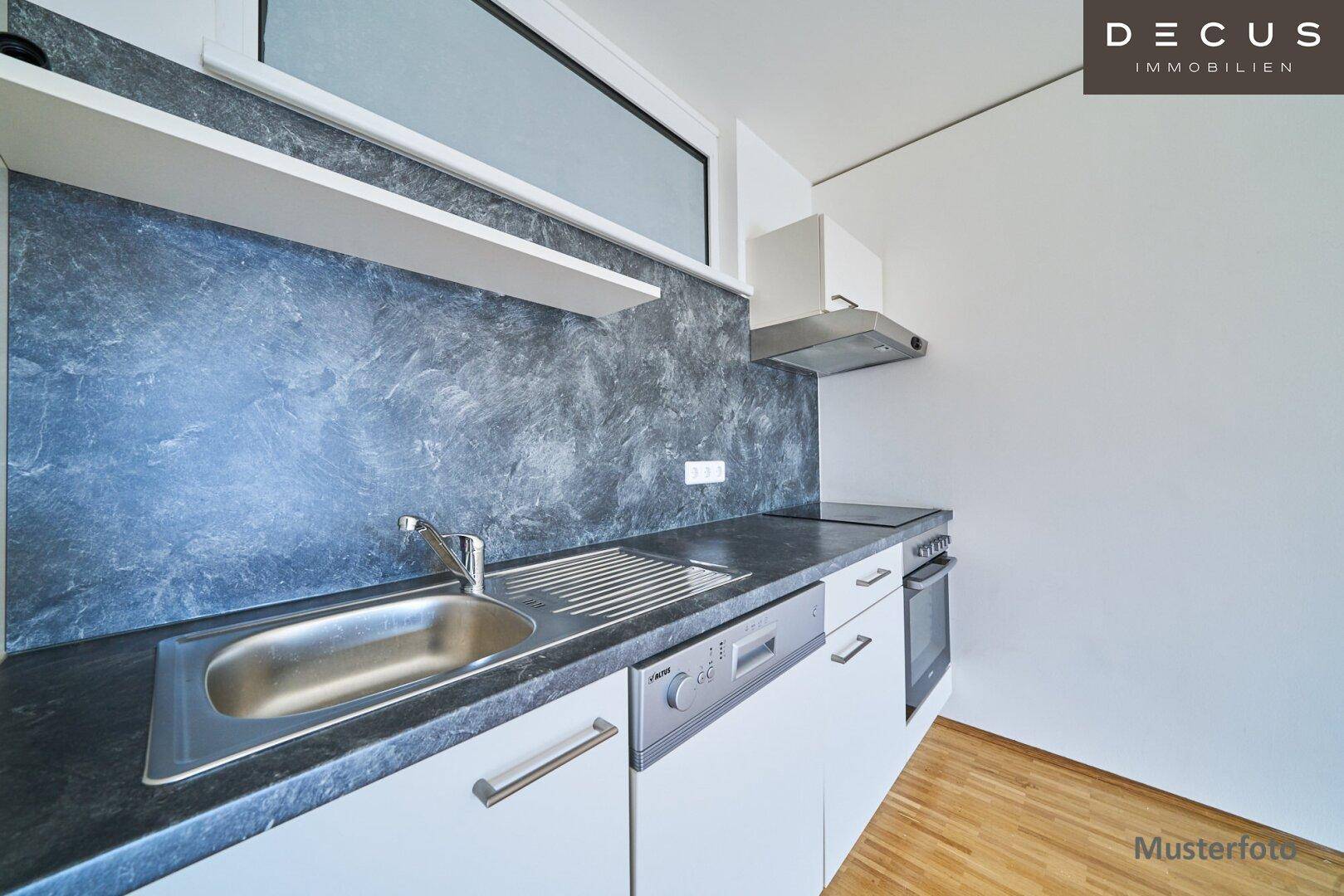 Moderne Einbauküche mit weißen Schränken, dunkler Arbeitsplatte und integrierten Geräten.
