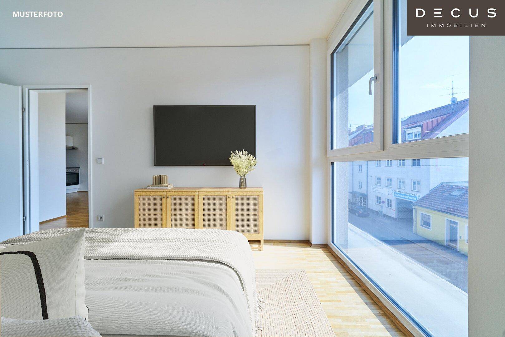 Helles Schlafzimmer mit großen Fenstern und Blick auf die städtische Umgebung.