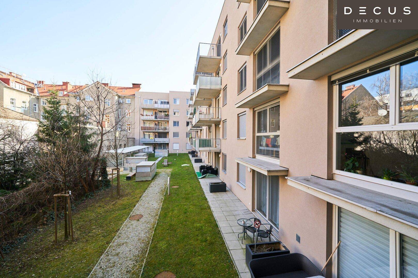 Außenansicht eines modernen Wohngebäudes mit Balkonen und einem gepflegten Gemeinschaftsgarten.
