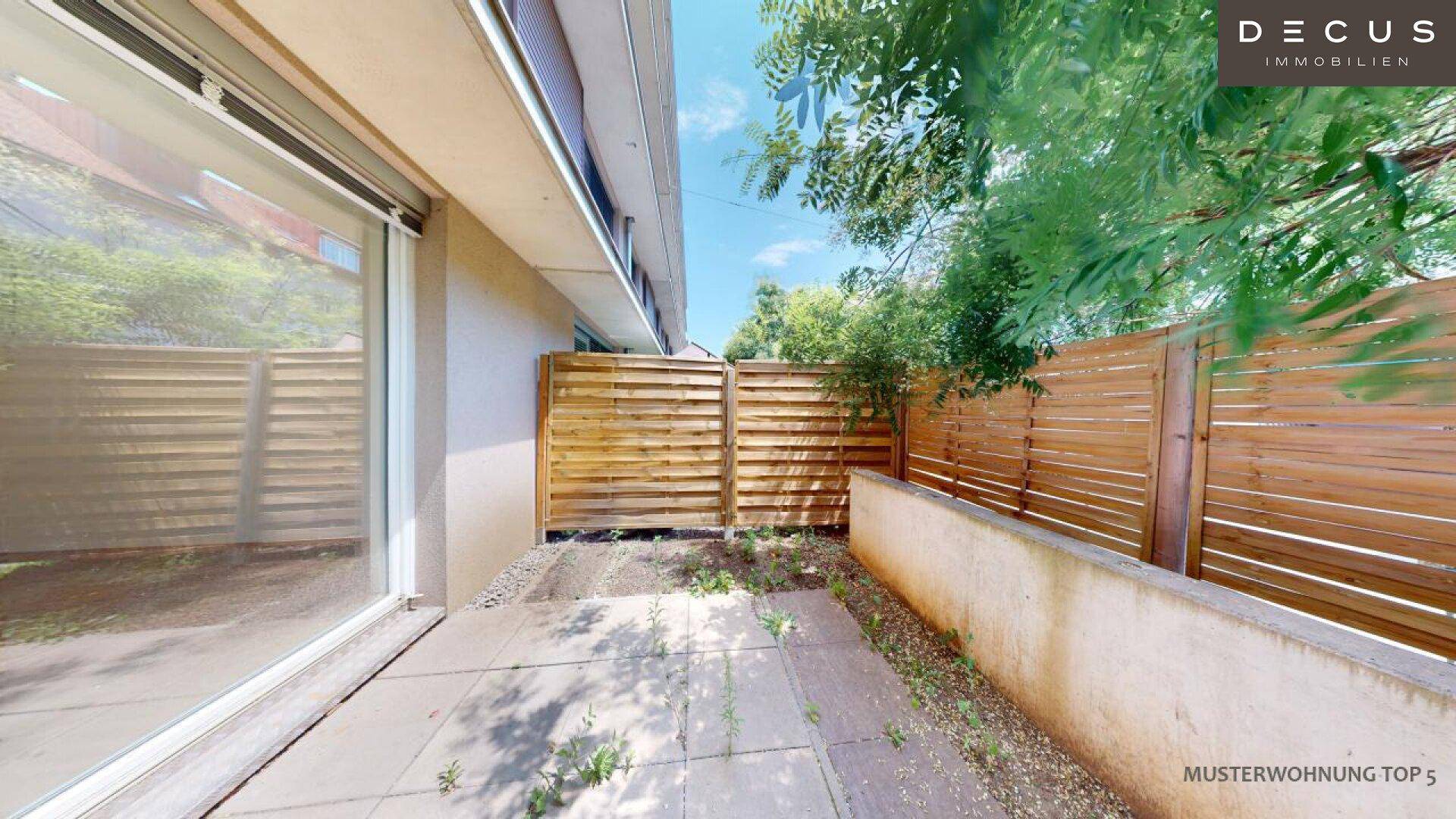 Kleine gepflasterte Terrasse mit Holzzaun, bietet Platz für einen gemütlichen Außenbereich.