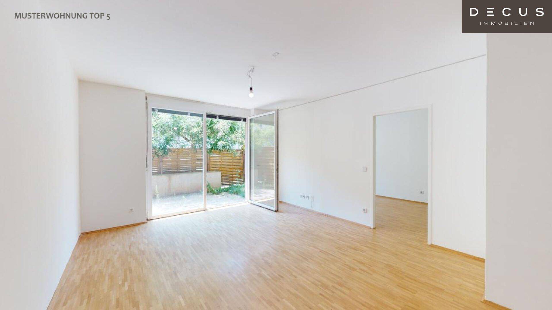 Heller Wohnraum mit Holzboden und großen Schiebetüren zum Garten oder zur Terrasse.