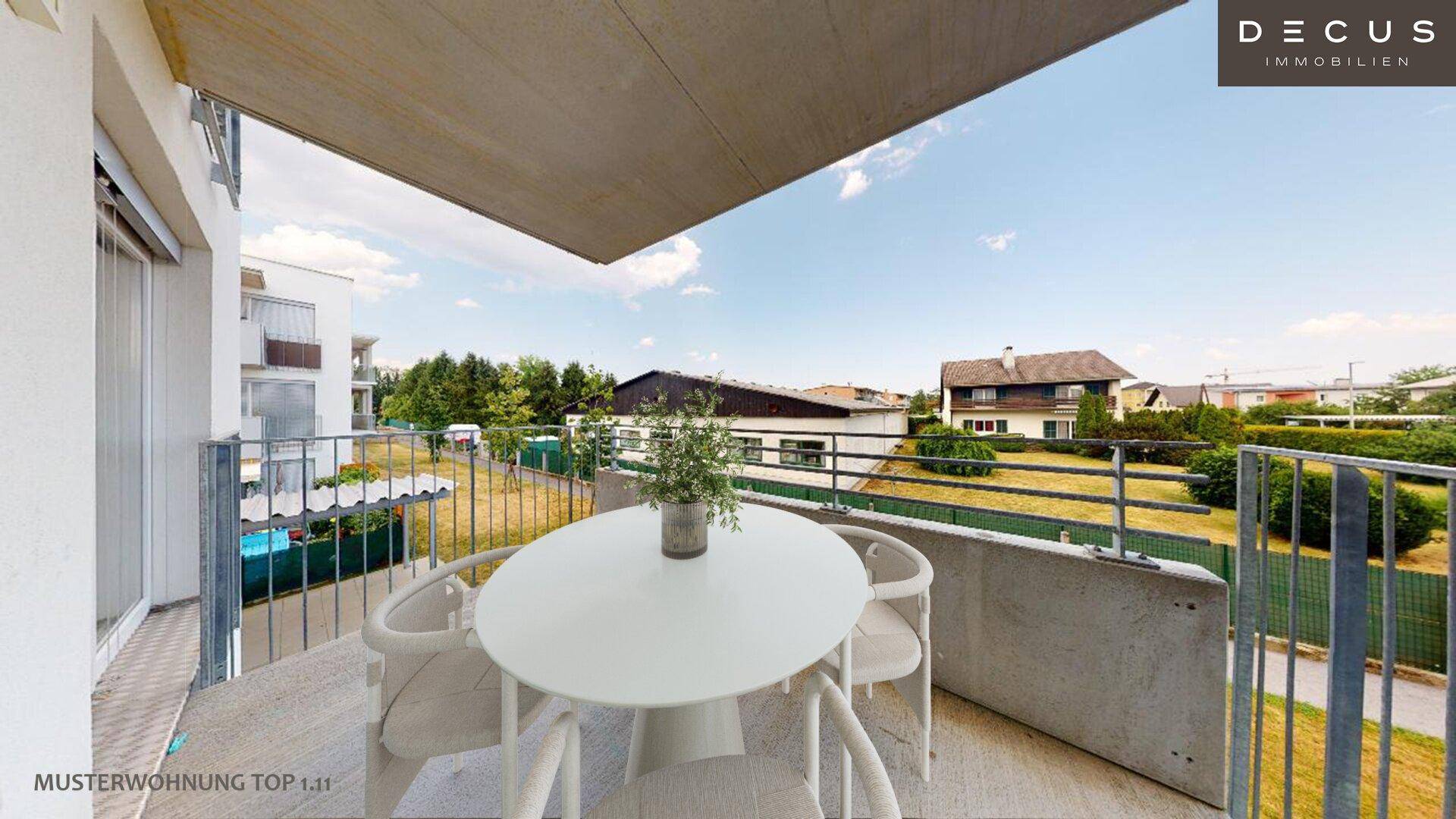 Runder Balkon mit Gartenmöbeln und Blick auf eine grüne Umgebung mit Einfamilienhäusern.