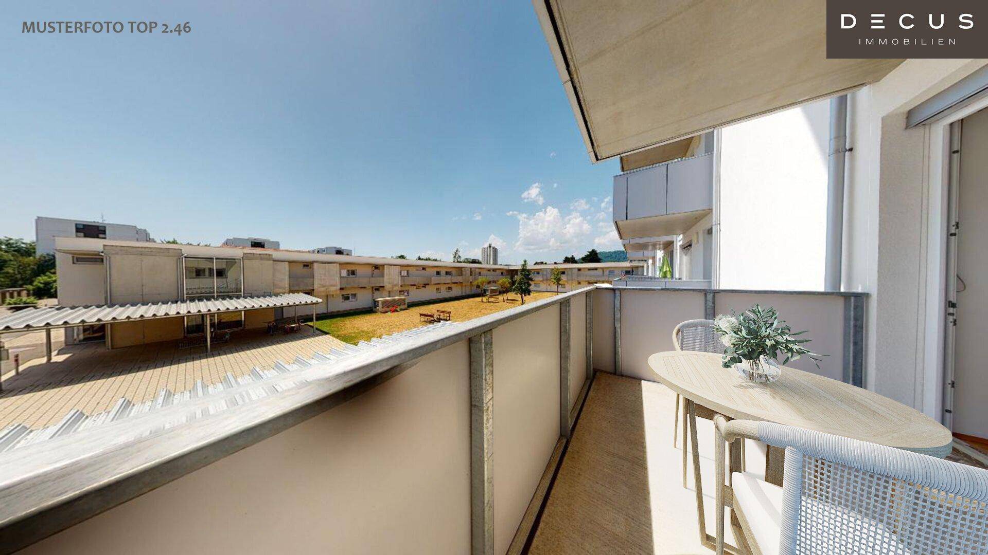 Balkon mit Sitzgelegenheiten und Blick auf einen Innenhof mit Spielplatz und umliegenden Gebäuden.