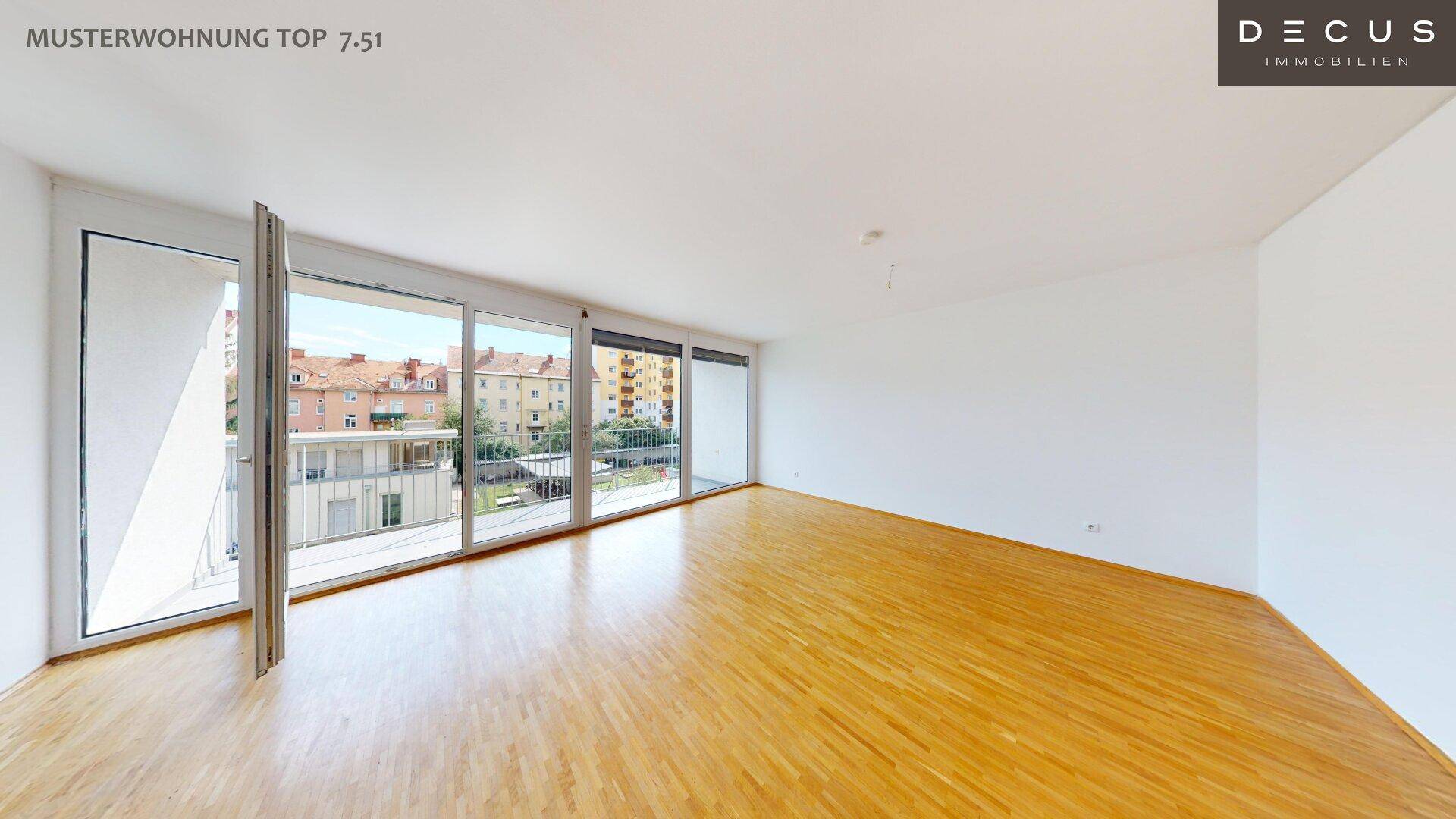 Heller Wohnbereich mit Holzboden und großen Fenstern, die viel Tageslicht hereinlassen und Zugang zum Balkon bieten.