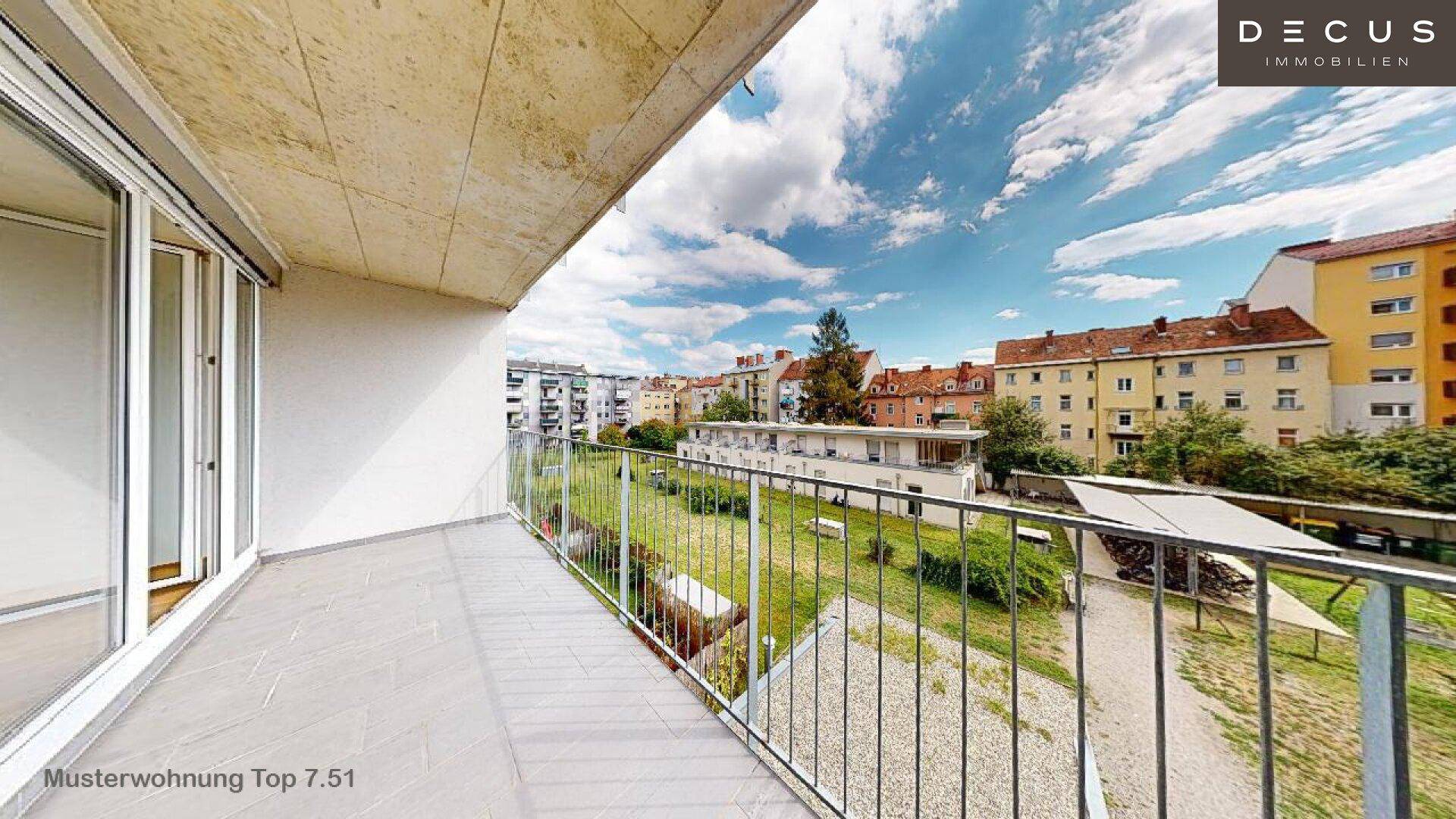 Langer Balkon mit Fliesenboden und Blick auf die umliegenden Gebäude und den grünen Innenhof.