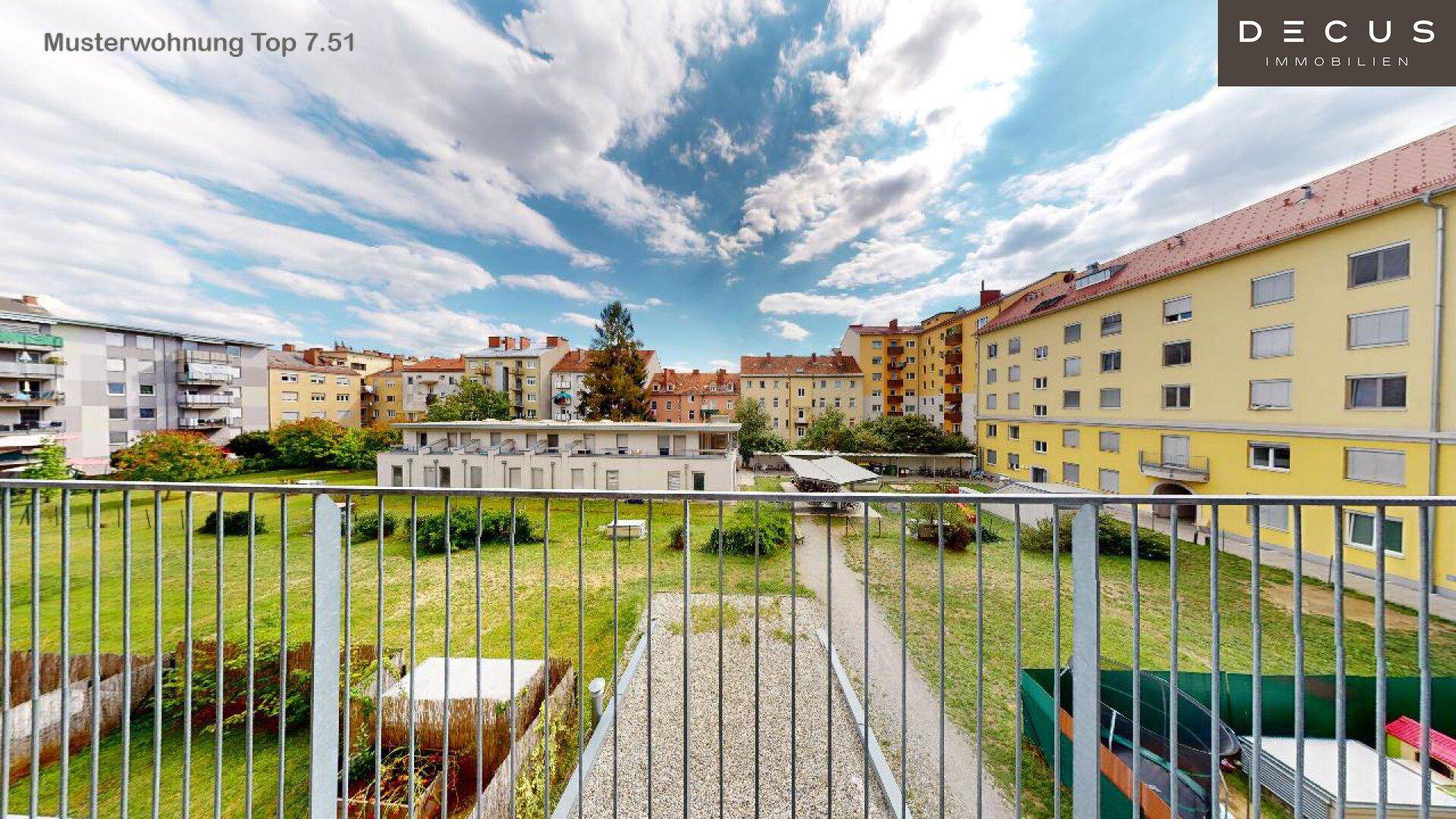 Weitläufiger Blick von einem Balkon auf einen grünen Innenhof und die umliegende Wohnbebauung.