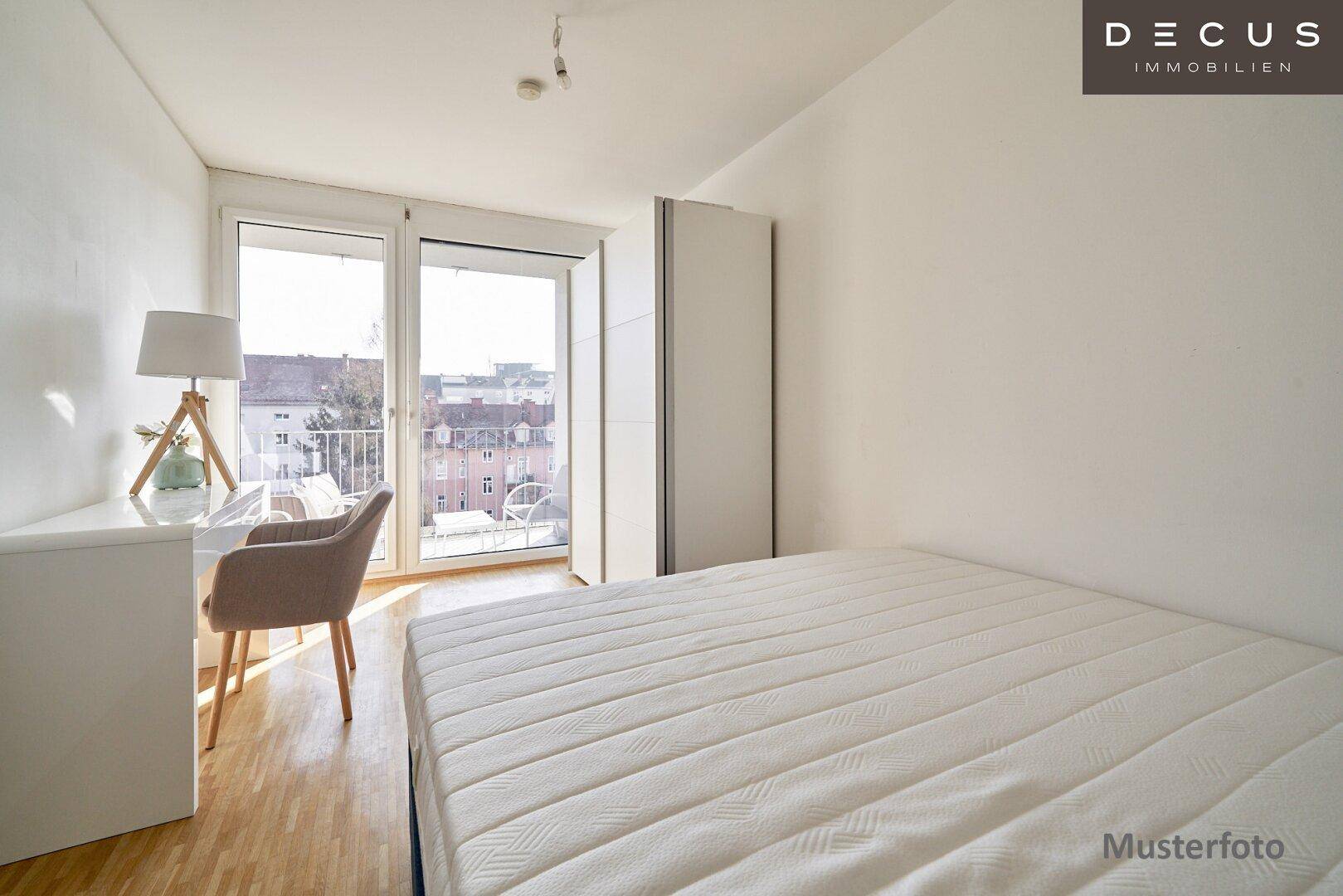Helles Schlafzimmer mit Holzboden, Schreibtisch und großem Fenster mit Blick nach draußen.