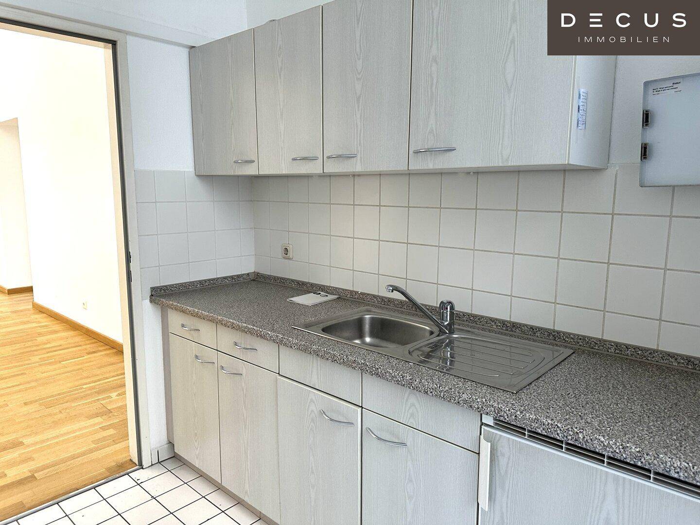 Funktionale Küche mit hellgrauen Schränken, Fliesenrückwand und Spülbecken, gut gepflegt.
