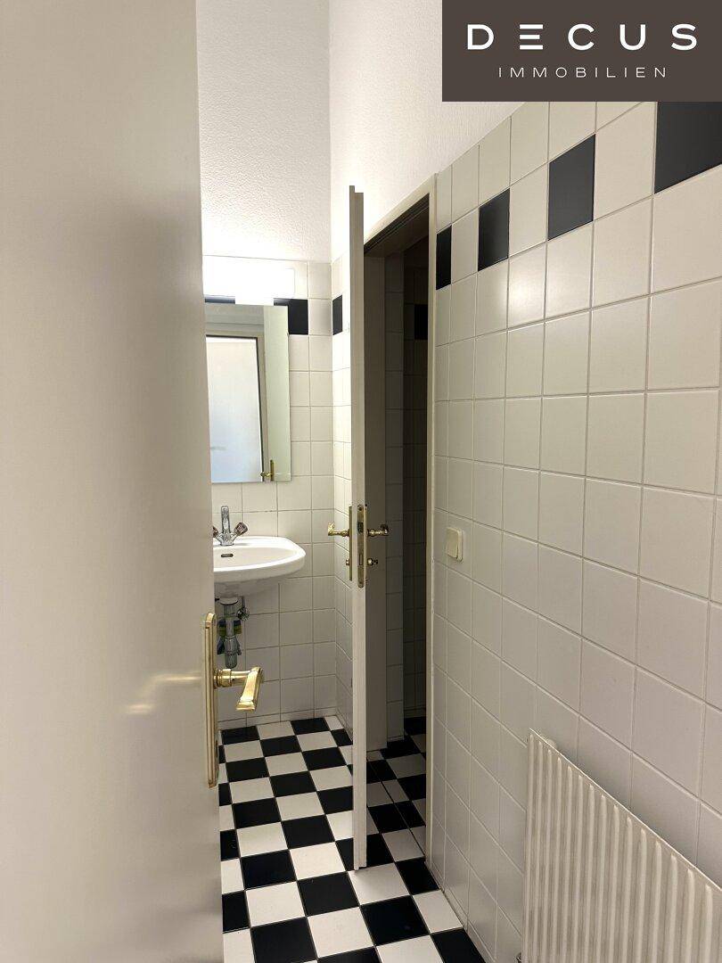 Badezimmer mit schwarz-weiß kariertem Fliesenboden und weißen Wandfliesen, klassisches Design.
