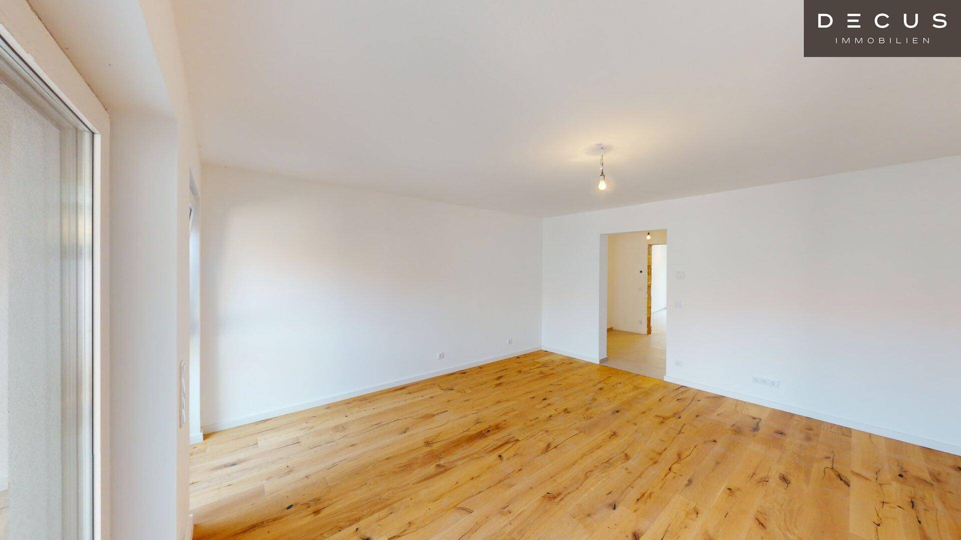 Heller Wohnbereich mit Holzboden und viel Tageslicht, bereit für individuelle Einrichtung.