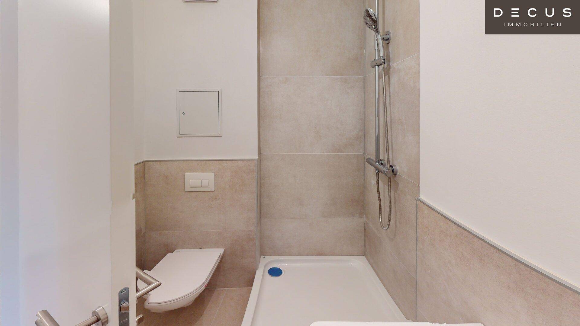 Modernes Badezimmer mit Dusche, Wand-WC und hellen Fliesen.