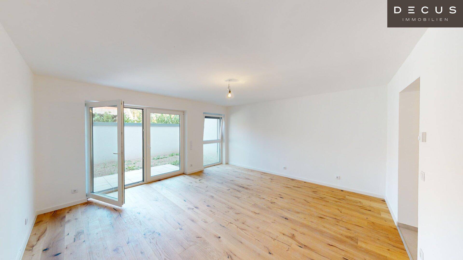 Lichtdurchfluteter Wohnbereich mit Holzboden und großen Fenstern zum Außenbereich.
