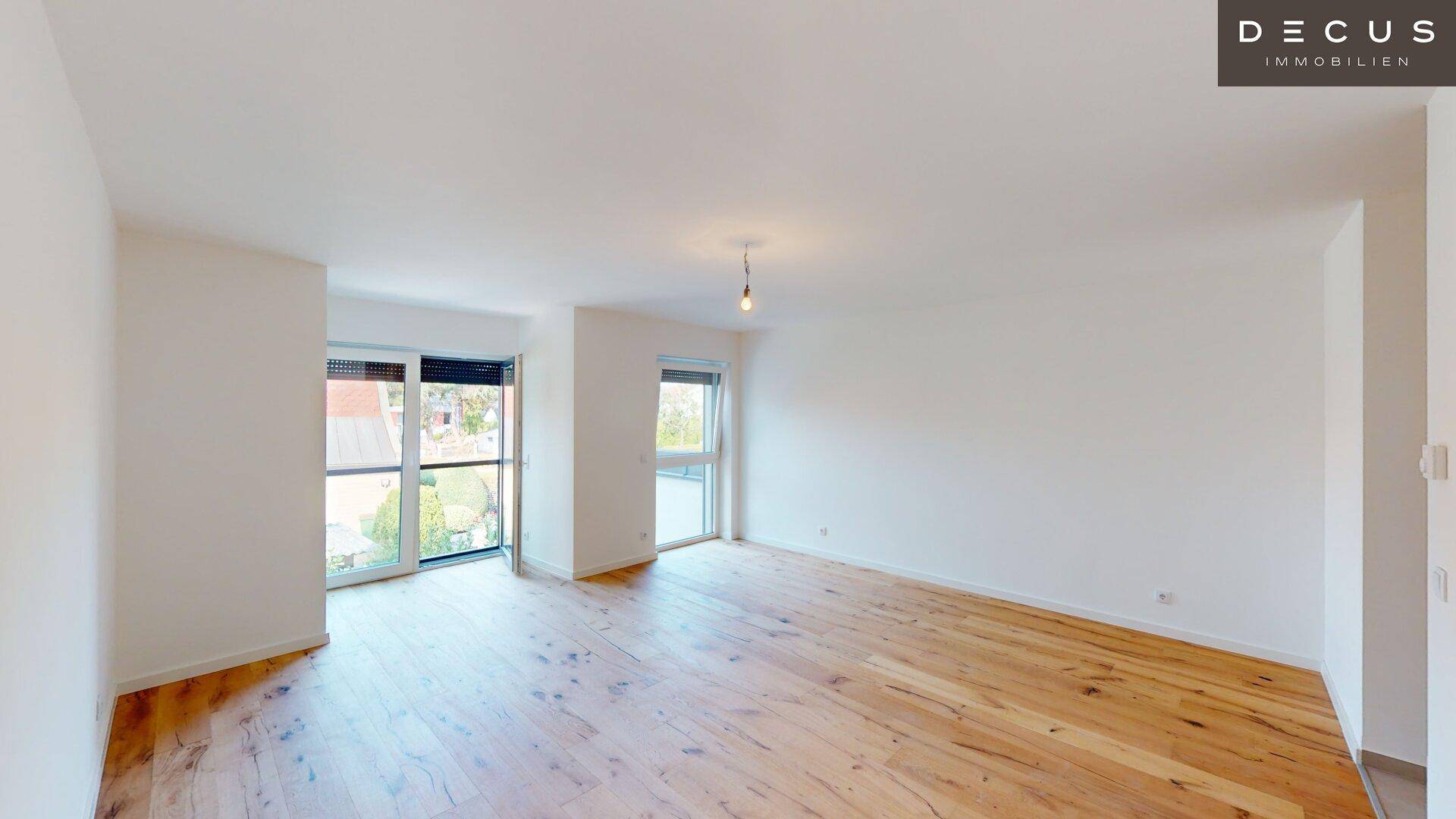 Geräumiger Wohnbereich mit hellem Holzboden und Fenstern mit Rollläden für Privatsphäre.