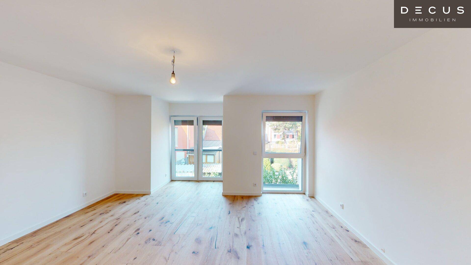 Lichtdurchfluteter Wohnraum mit Holzboden und großen Fenstern, die eine angenehme Atmosphäre schaffen.