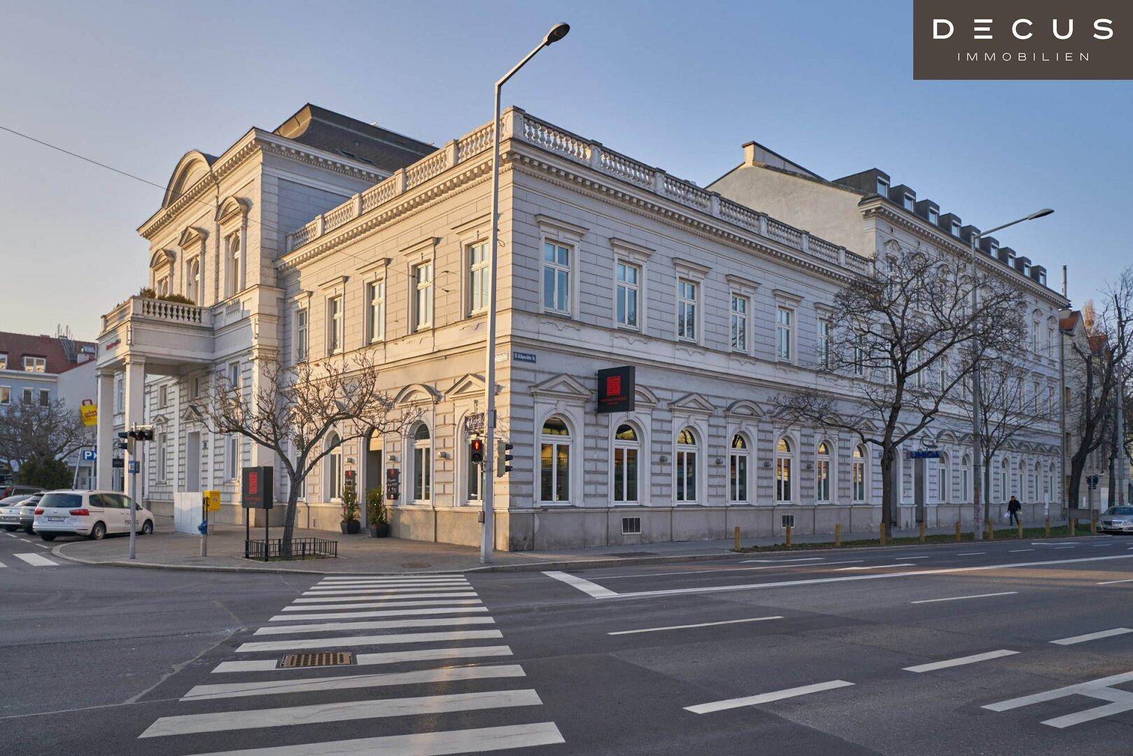 Historisches Gebäude an einer Straßenecke mit klassischer Architektur und belebter Umgebung.