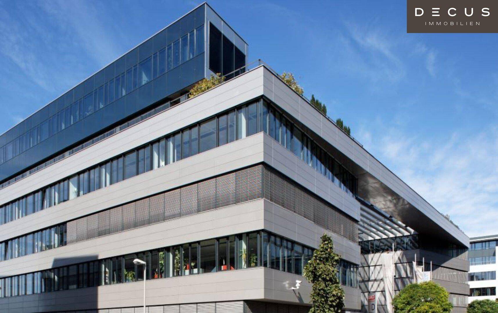 Modernes Bürogebäude mit markanter Glasfassade und klaren architektonischen Linien unter blauem Himmel.