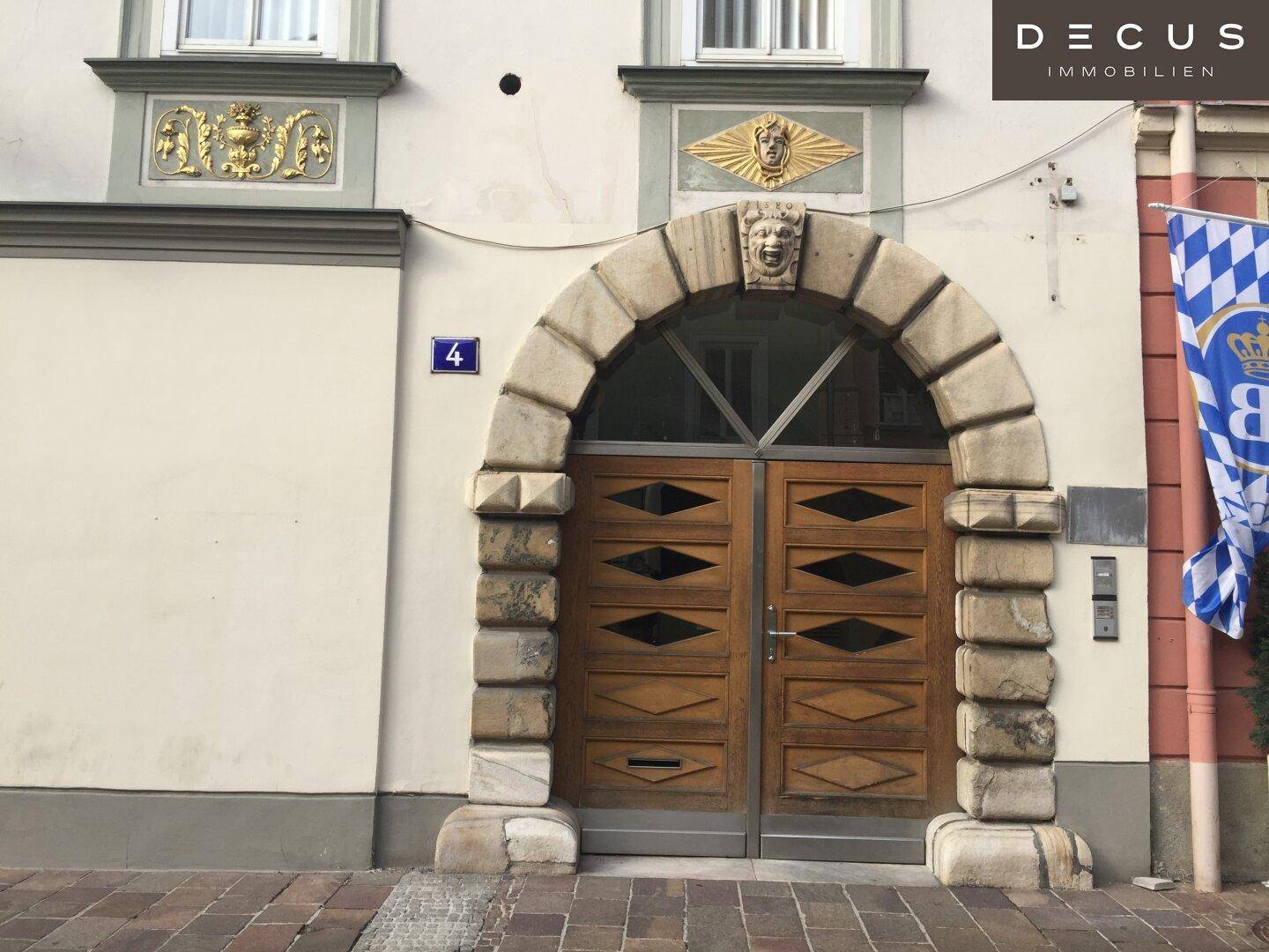 Historischer Gebäudeeingang mit einem markanten Steinbogen und einer verzierten Holztür.