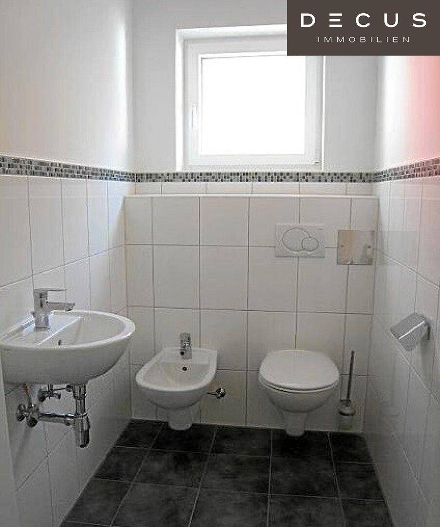 Gäste-WC mit Waschbecken, Bidet und Toilette, ausgestattet mit weißen Fliesen.