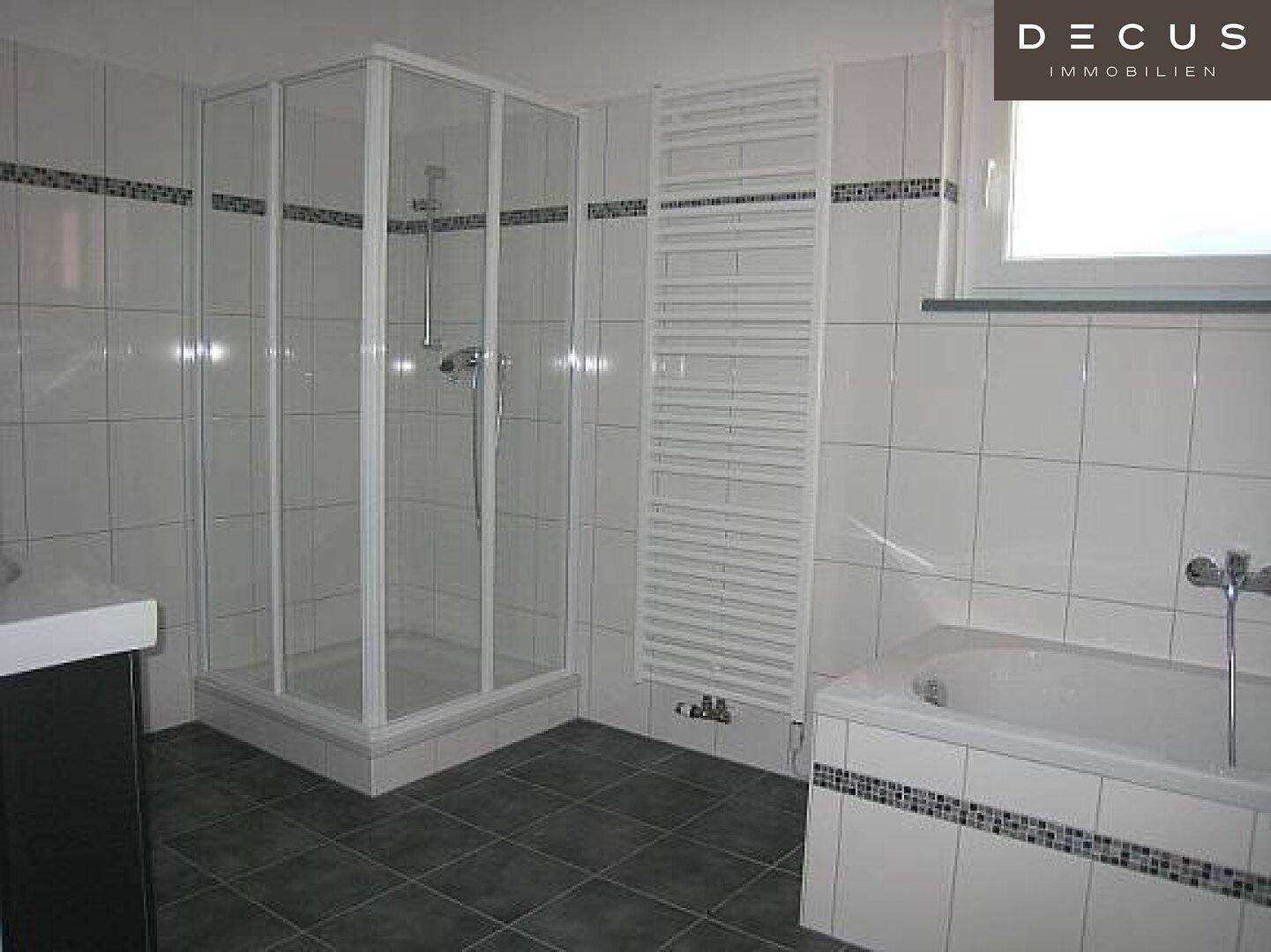 Badezimmer mit Duschkabine, Badewanne, Waschbecken und beheiztem Handtuchhalter.