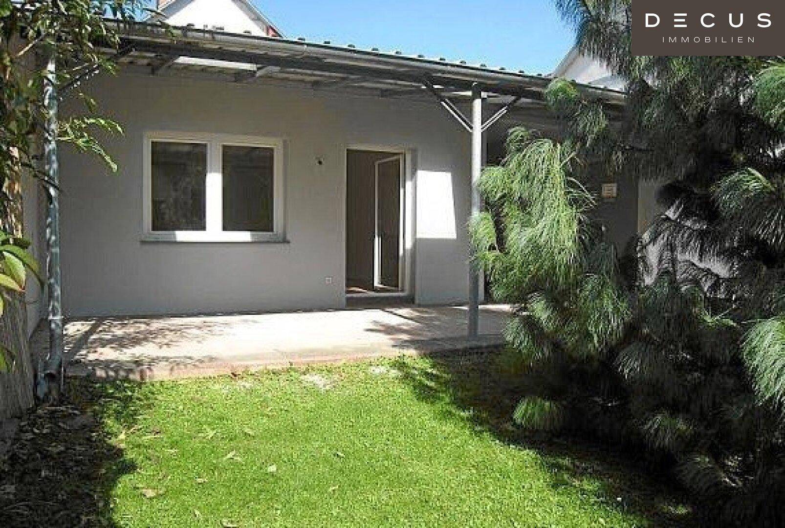 Überdachte Terrasse mit Zugang zum Haus und Blick auf den grünen Garten.
