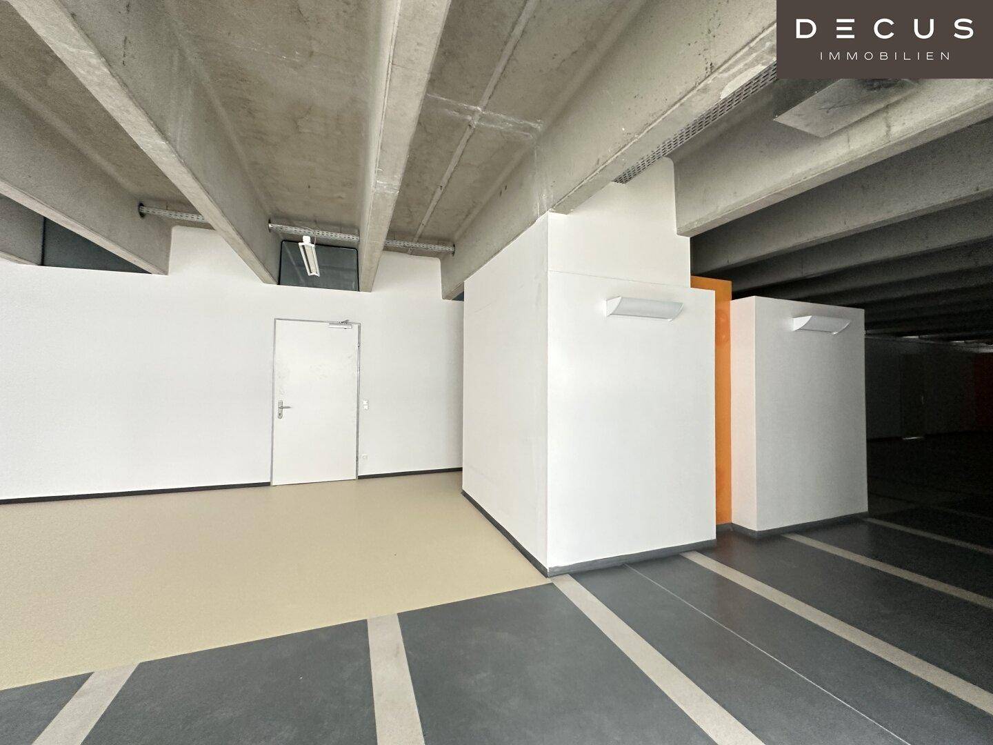 Flurbereich mit Betondecke, gefliestem Boden und einer weißen Wand mit einem orangefarbenen Akzent.