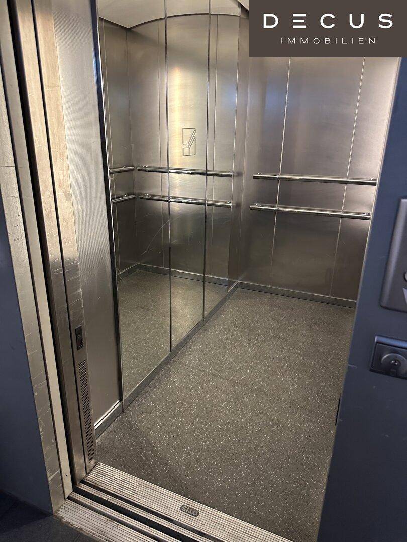 Innenansicht eines modernen Aufzugs mit Edelstahlwänden und Spiegeln, die den Raum vergrößern.