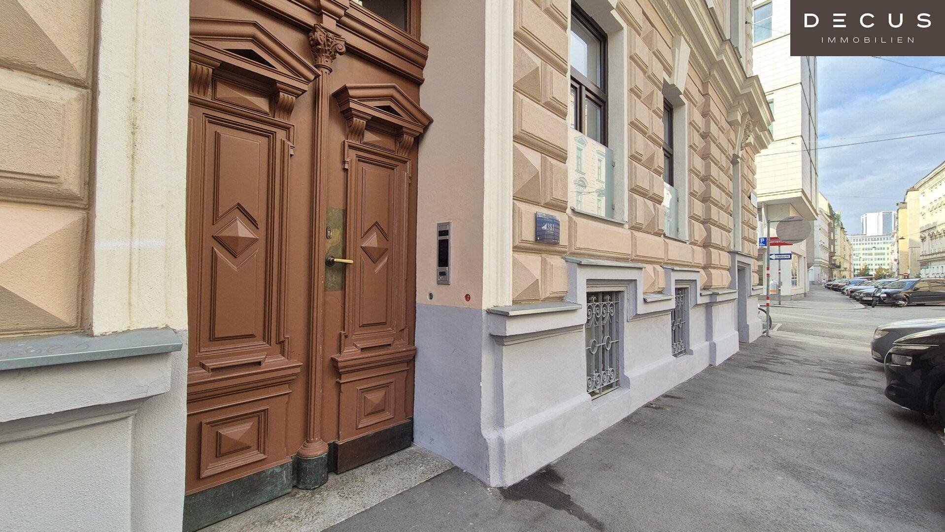 Historisches Gebäude mit verzierter Holztür und Blick auf die Straße in einem städtischen Umfeld.