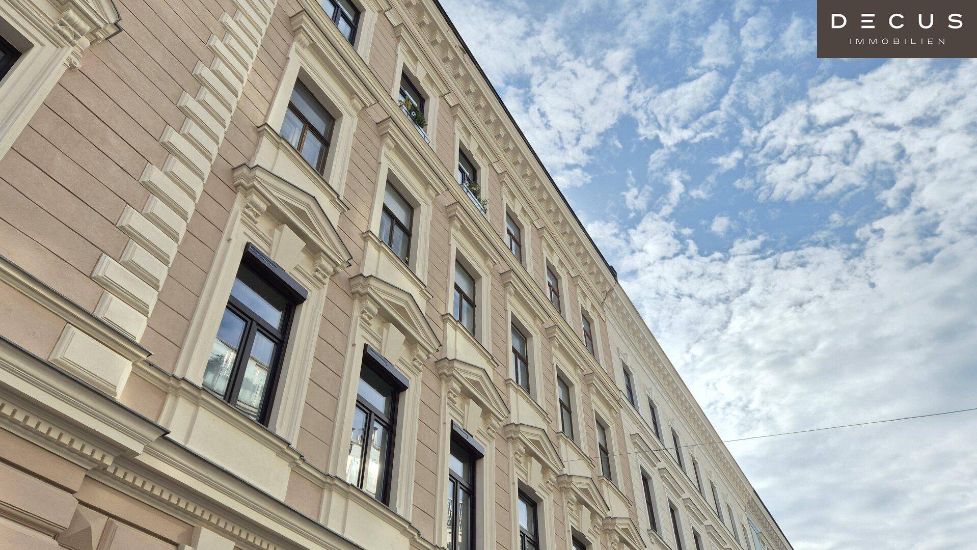 Detailansicht der oberen Etagen eines historischen Gebäudes mit vielen Fenstern und Stuckverzierungen.