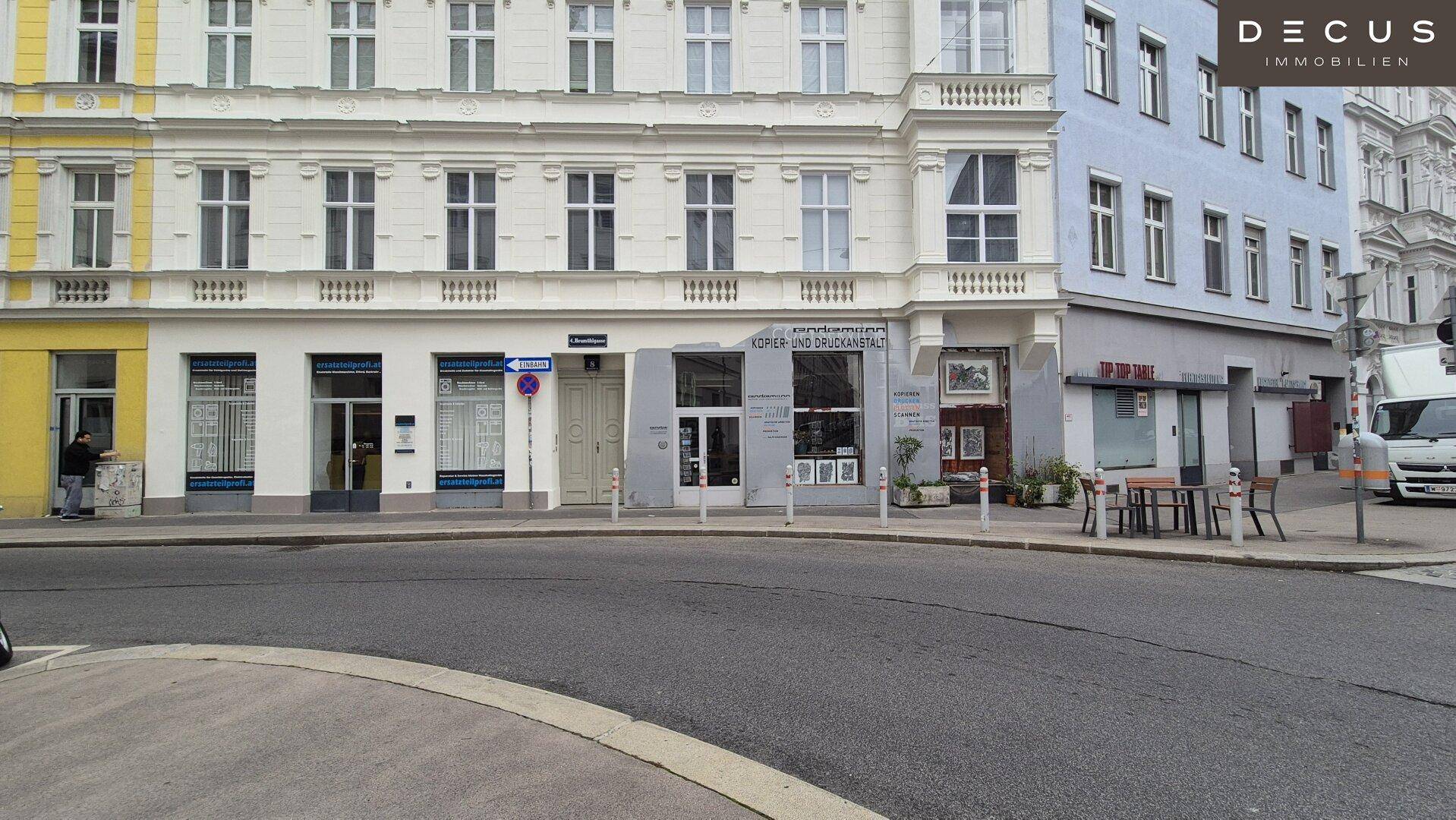 Erdgeschossfassade eines historischen Gebäudes mit Geschäften und einem kleinen Außenbereich.