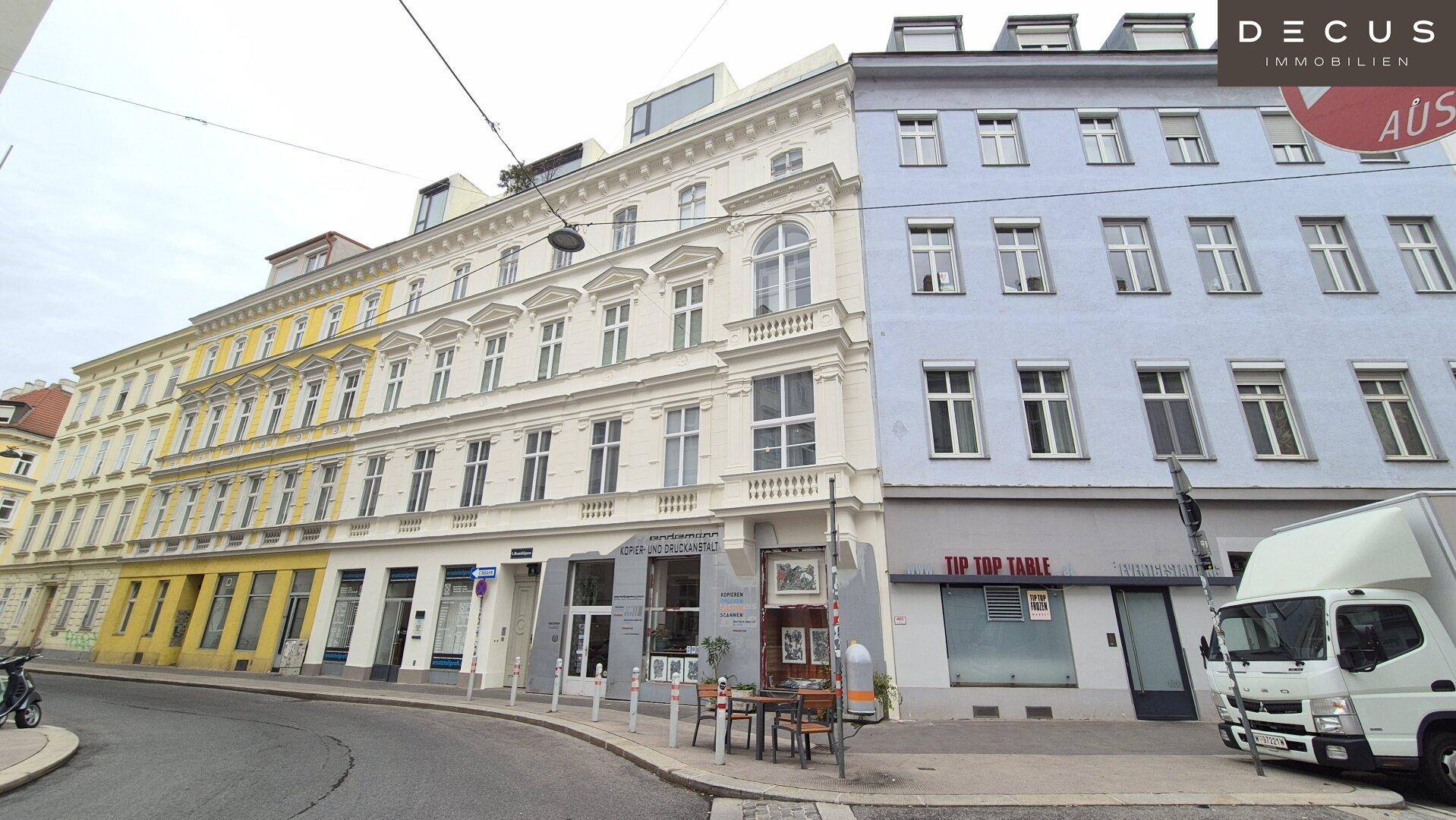 Mehrere historische Gebäude mit unterschiedlichen Fassadenfarben entlang einer belebten Stadtstraße.