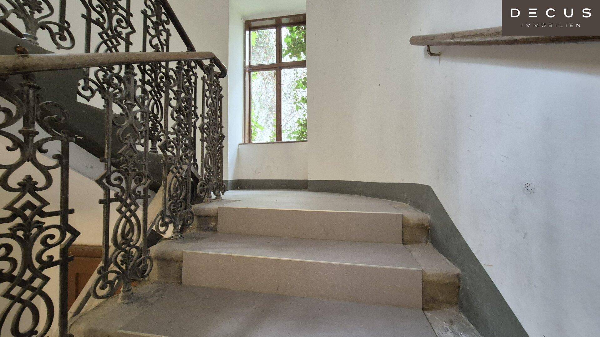 Detailansicht eines historischen Treppenhauses mit schmiedeeisernem Geländer und Steinstufen.