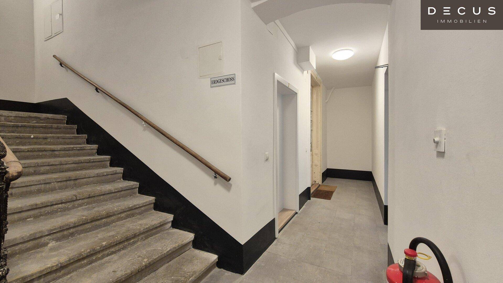 Geräumiger Treppenaufgang mit Steinstufen und einem Aufzug im Erdgeschoss des Gebäudes.