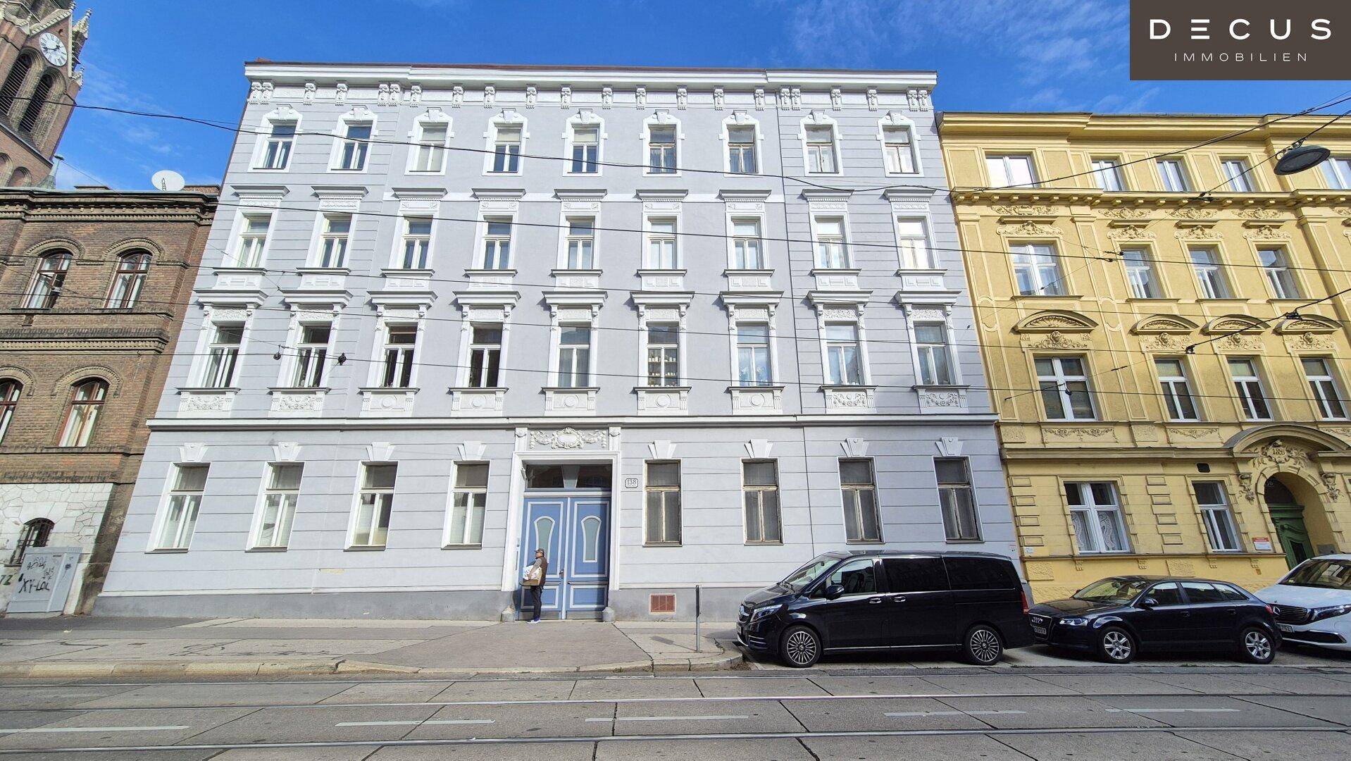 Klassisches Mehrfamilienhaus mit historischer Fassade und blauer Eingangstür an einer Stadtstraße.