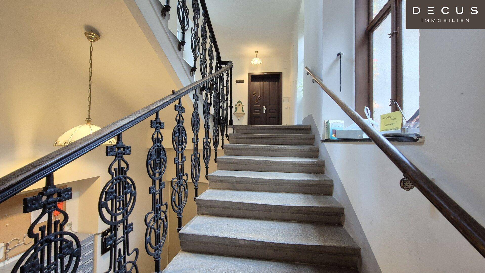 Historisches Treppenhaus mit kunstvollem schmiedeeisernem Geländer und breiten Steinstufen.