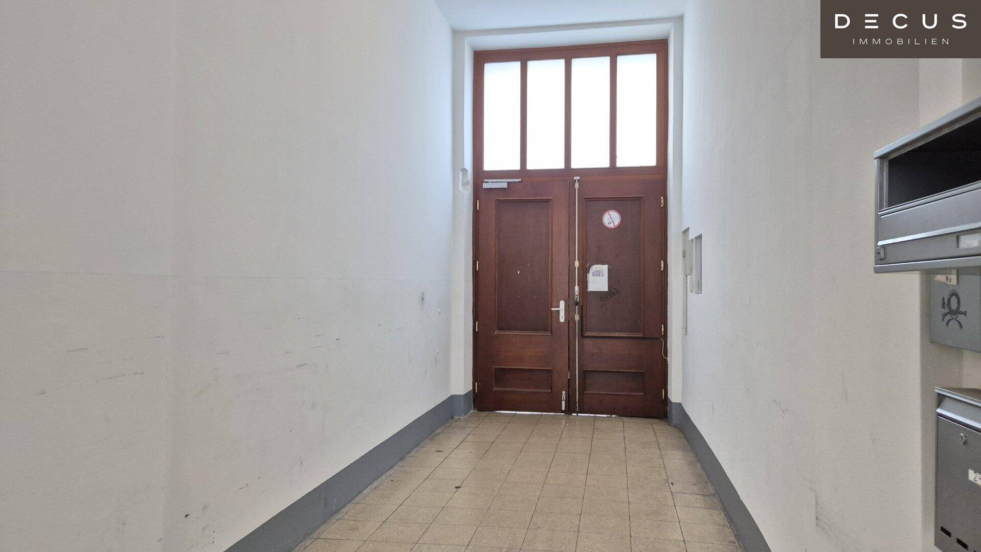 Große Holzeingangstür mit Glaseinsätzen im Flur eines Altbaus, die viel Licht hereinlässt.